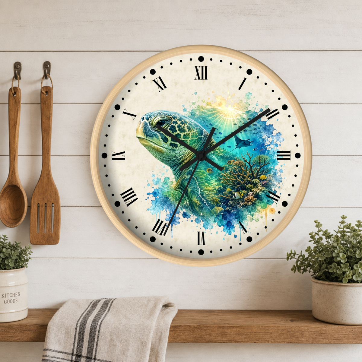 A round wall clock with a light wood frame hangs on a white wood plank wall above a wooden shelf. The clock face features a colorful watercolor painting of a sea turtle with blue, green, and yellow tones, Roman numerals, and black hands.