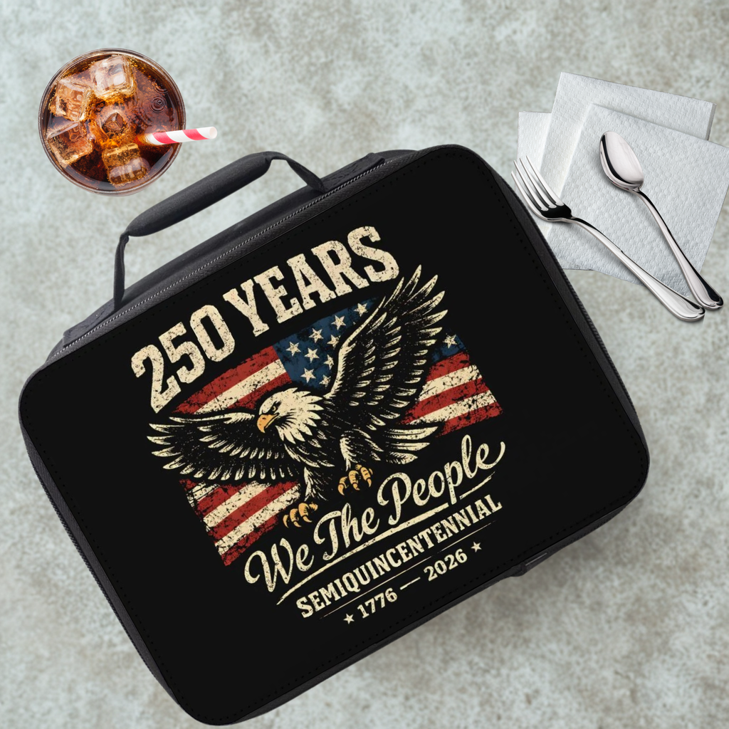 Black lunch box with eagle and American flag design on a gray table with a drink and utensils.