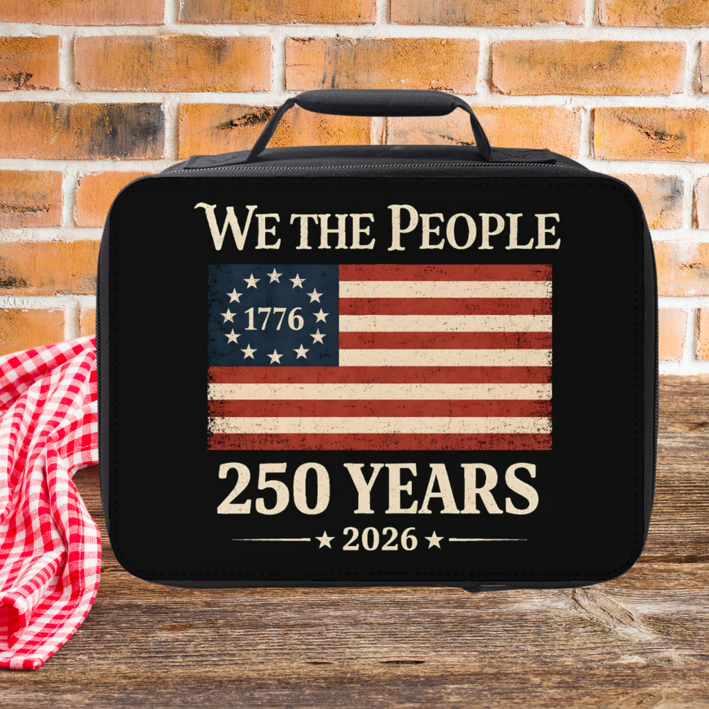 Black bag with American flag design and text 'We the People 1776 250 Years 2026' on a wooden picnic table with a brick wall background.