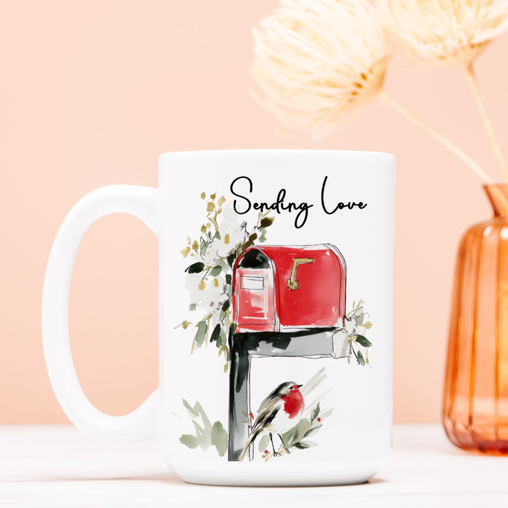 White mug with a red mailbox, bird, and floral design on a peach background