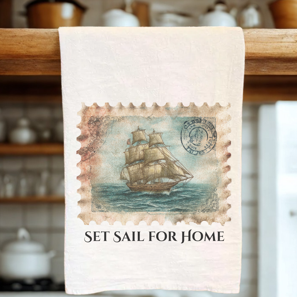 Tea towel with a ship design and 'Set Sail for Home' text on a wooden rack.