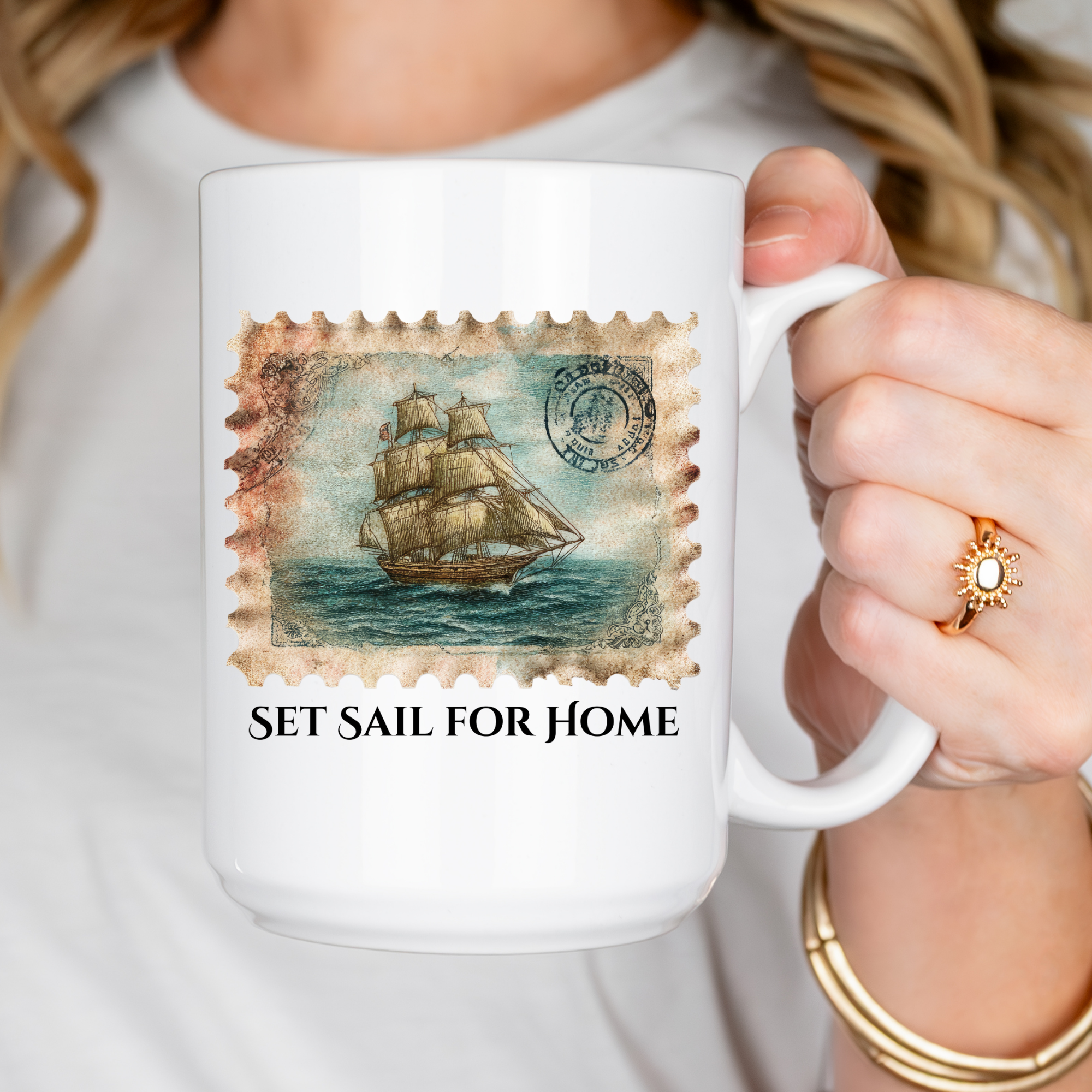 White mug with a ship stamp design and 'Set Sail for Home' text, held by a person.