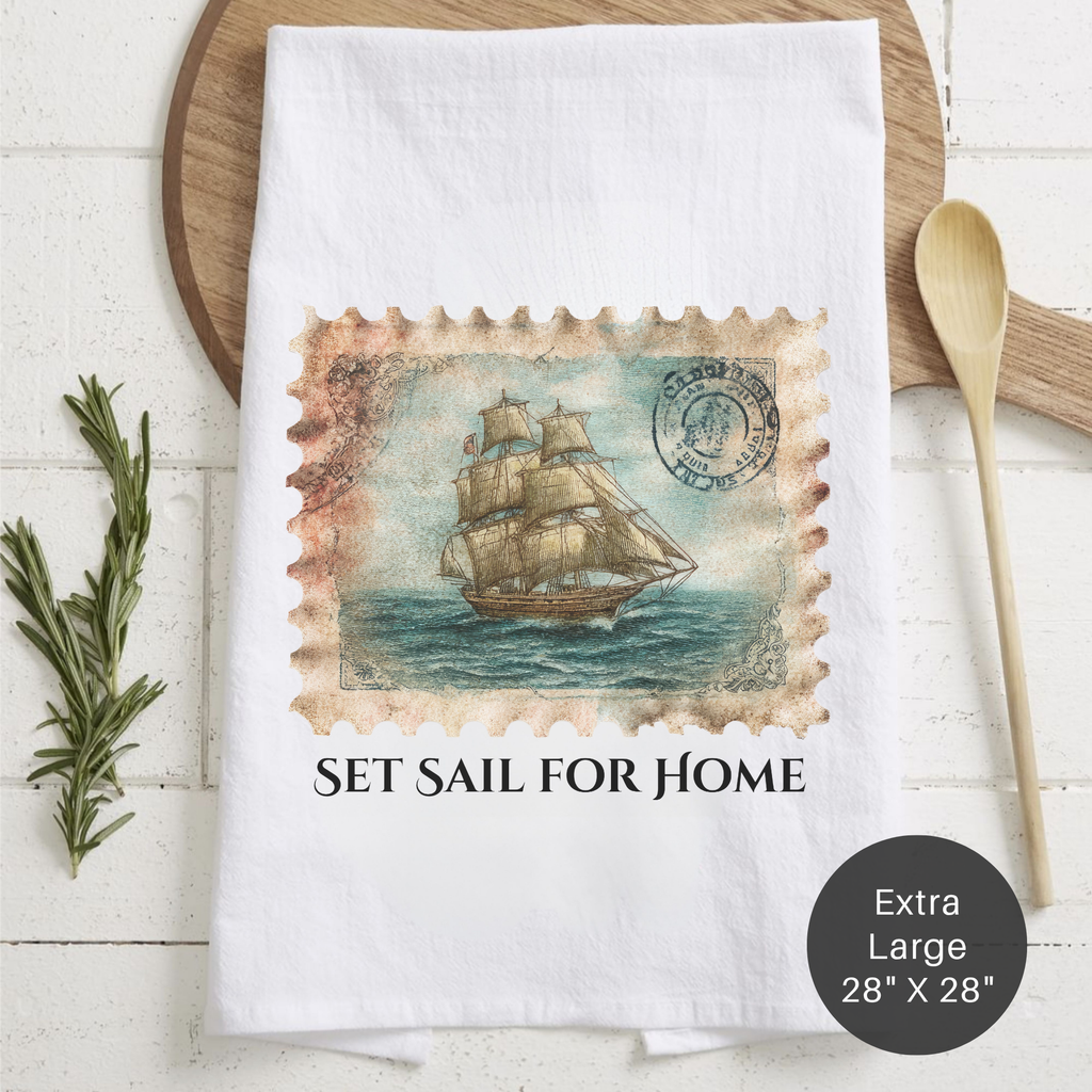 White towel with ship design and 'Set Sail for Home' text on a wooden surface.