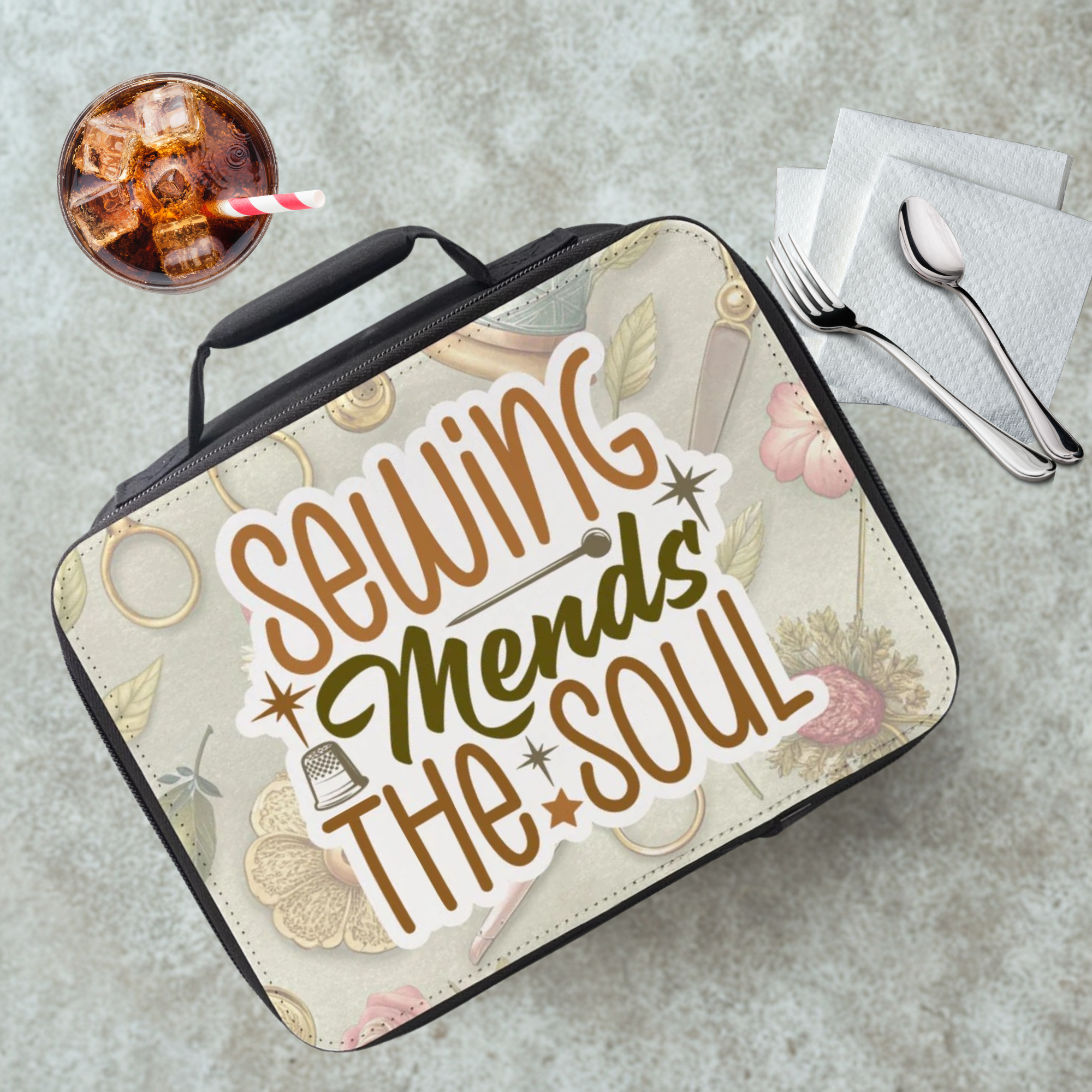 Lunch bag with 'Sewing Mends the Soul' text on a cafeteria table with a drink and utensils.