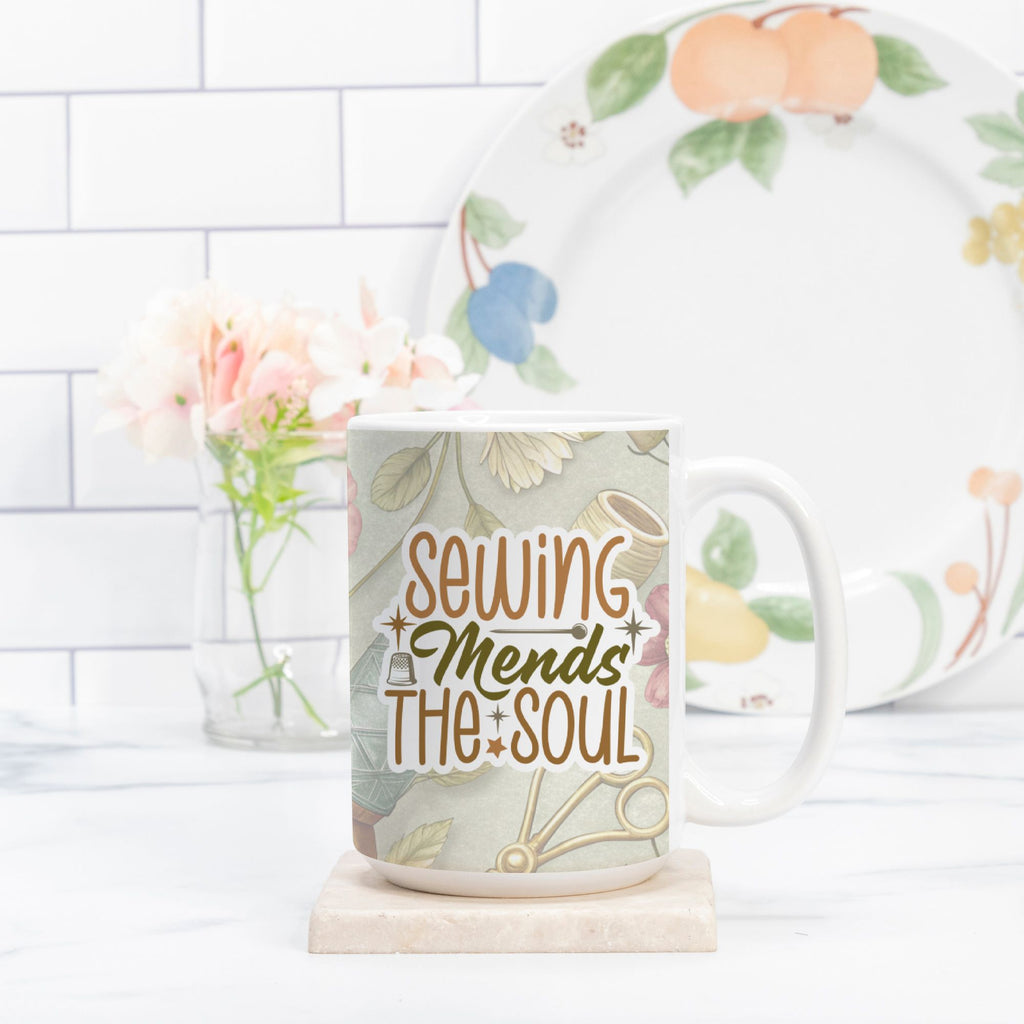 Mug with 'Sewing Mends The Soul' text on a floral background, next to a plate with fruit design.