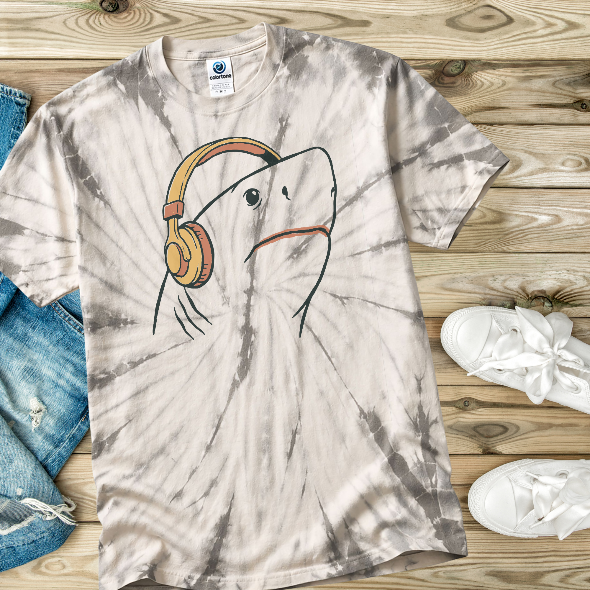 Tie-dye t-shirt in the color Spider Silver  with a hand drawn shark wearing headphones on a wooden surface.