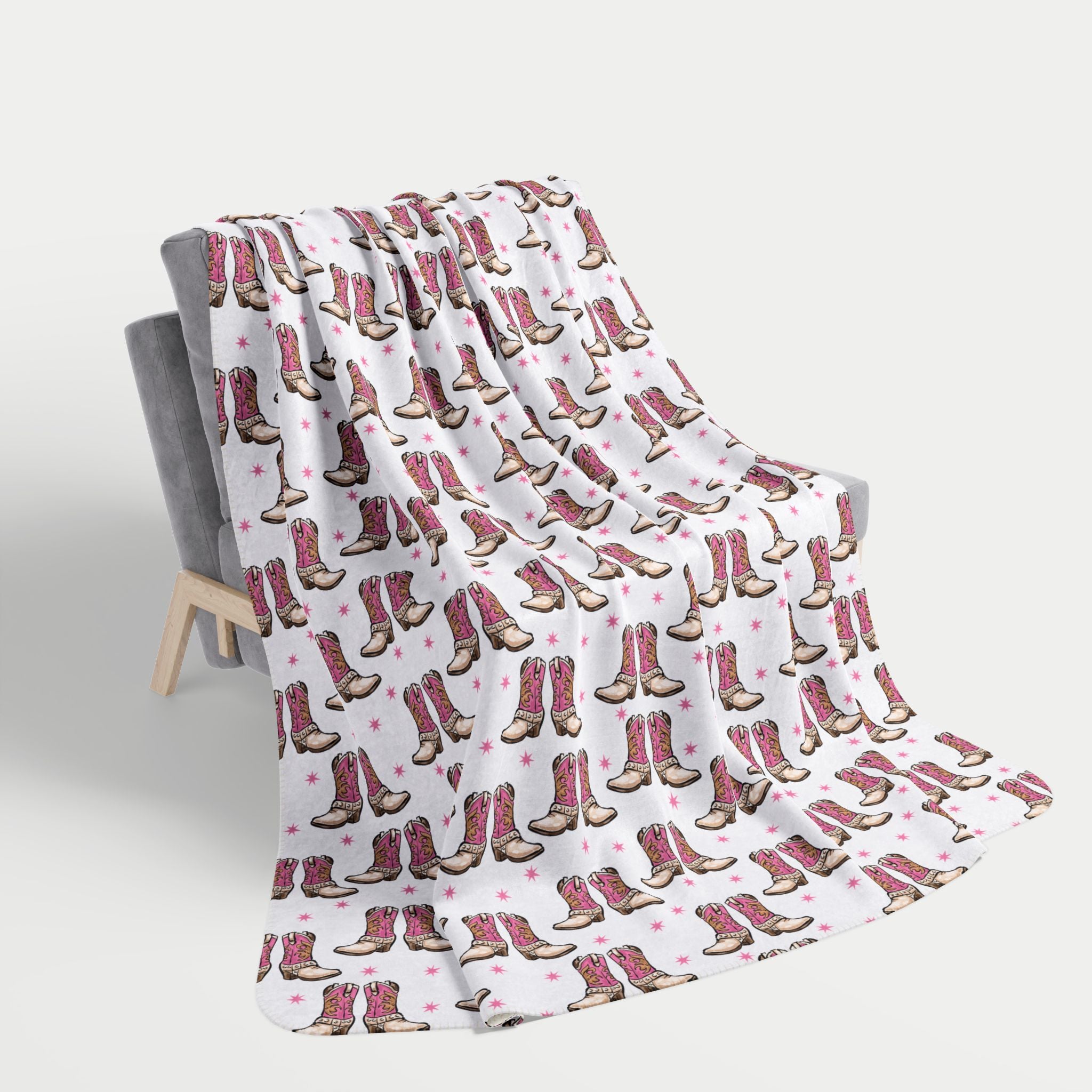Blanket with cowboy boot pattern draped over a chair on a white background