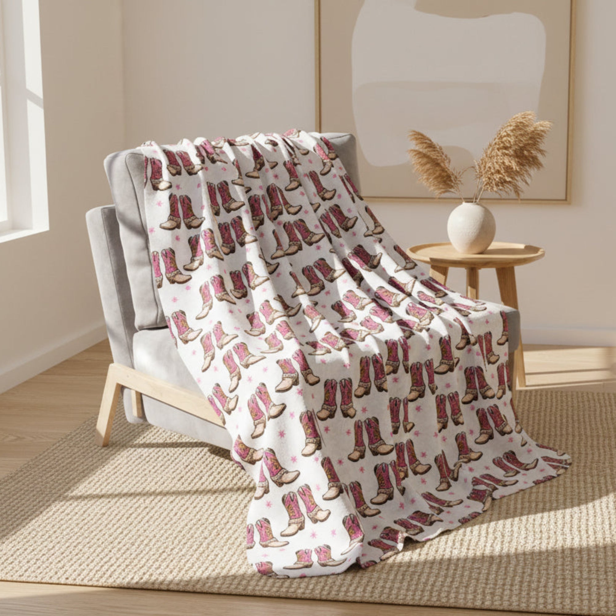 Blanket with pink cowboy boot pattern draped over a chair on a light gray background