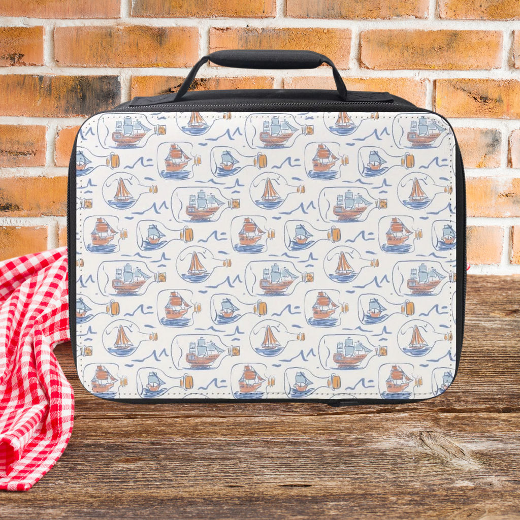 Lunch bag with hand drawn ships in bottles pattern on a wooden picnic table and brick wall background