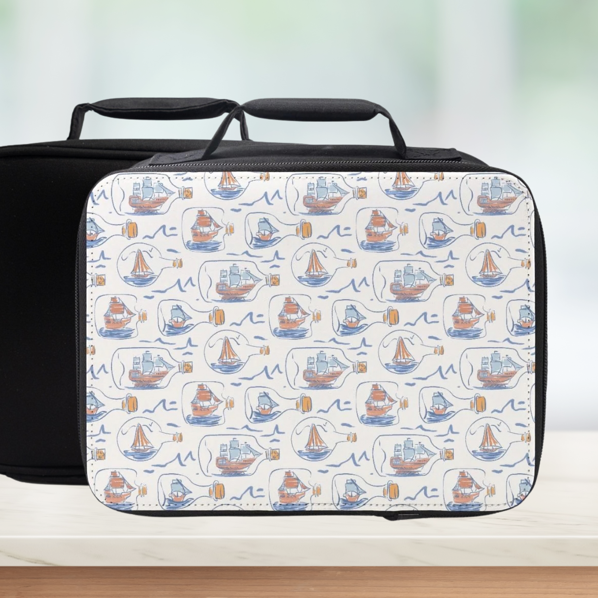 Black lunch bag with a white pattern of hand drawn ships in bottles on a light background