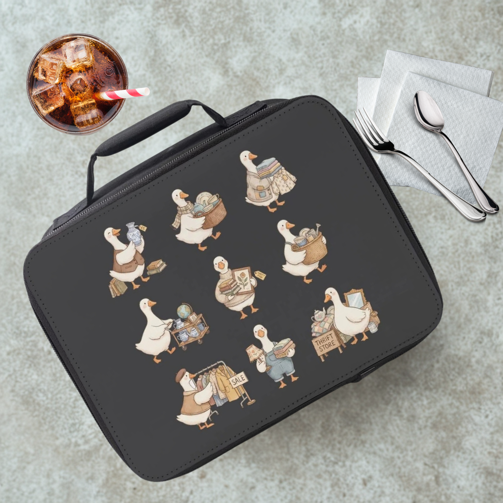 Black lunch bag with illustrated thrift shopping geese design on a gray table with a drink and utensils.