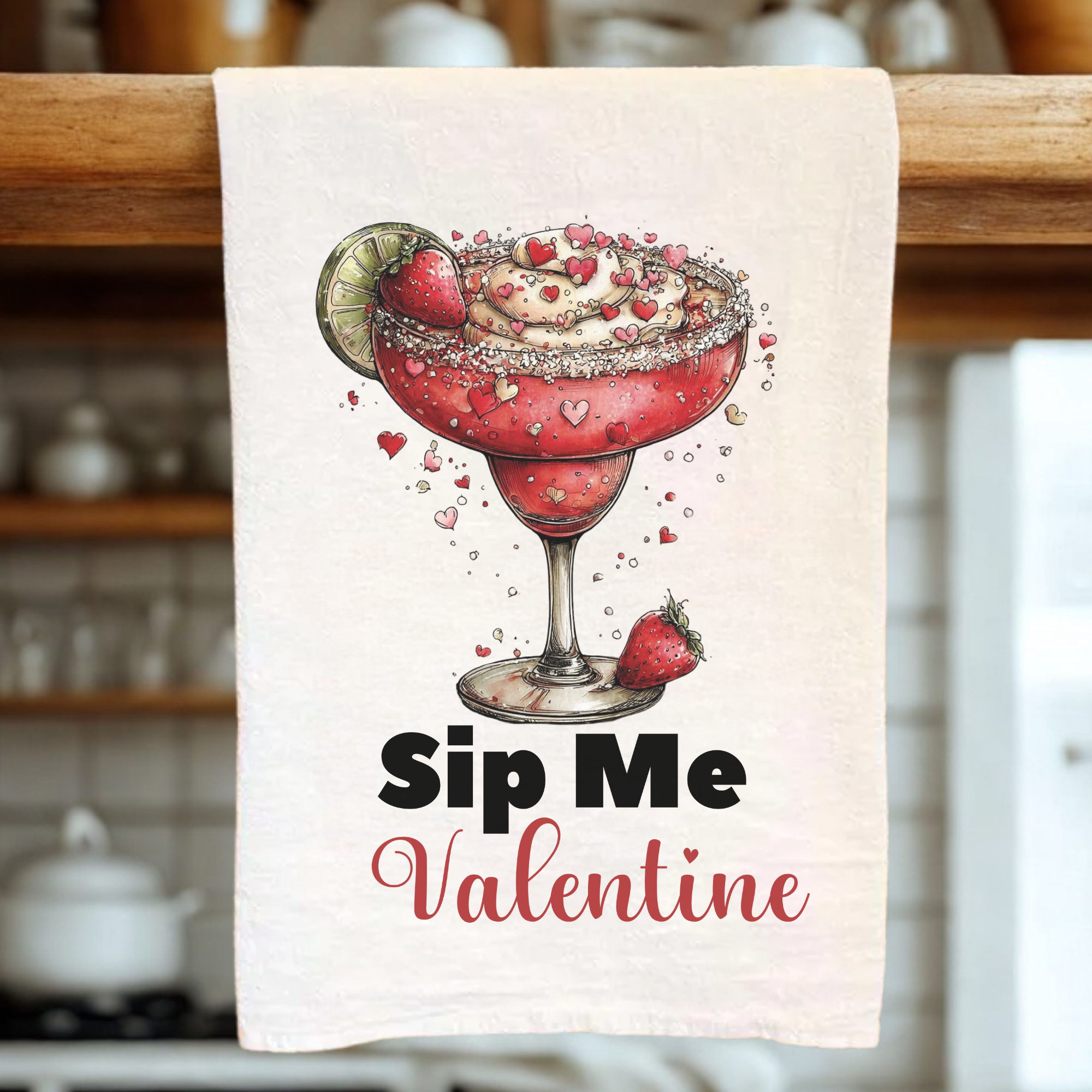 Kitchen towel with a Valentine's Day-themed design of a cocktail and text 'Sip Me Valentine' on a wooden rack.