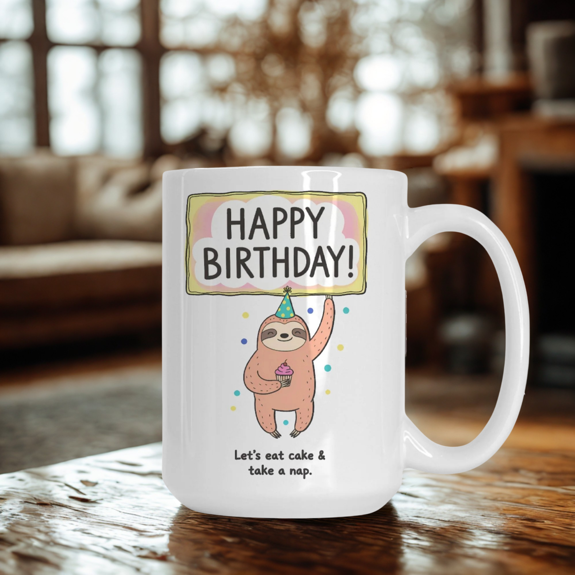 White mug with a sloth design and 'Happy Birthday!' text on a wooden table.
