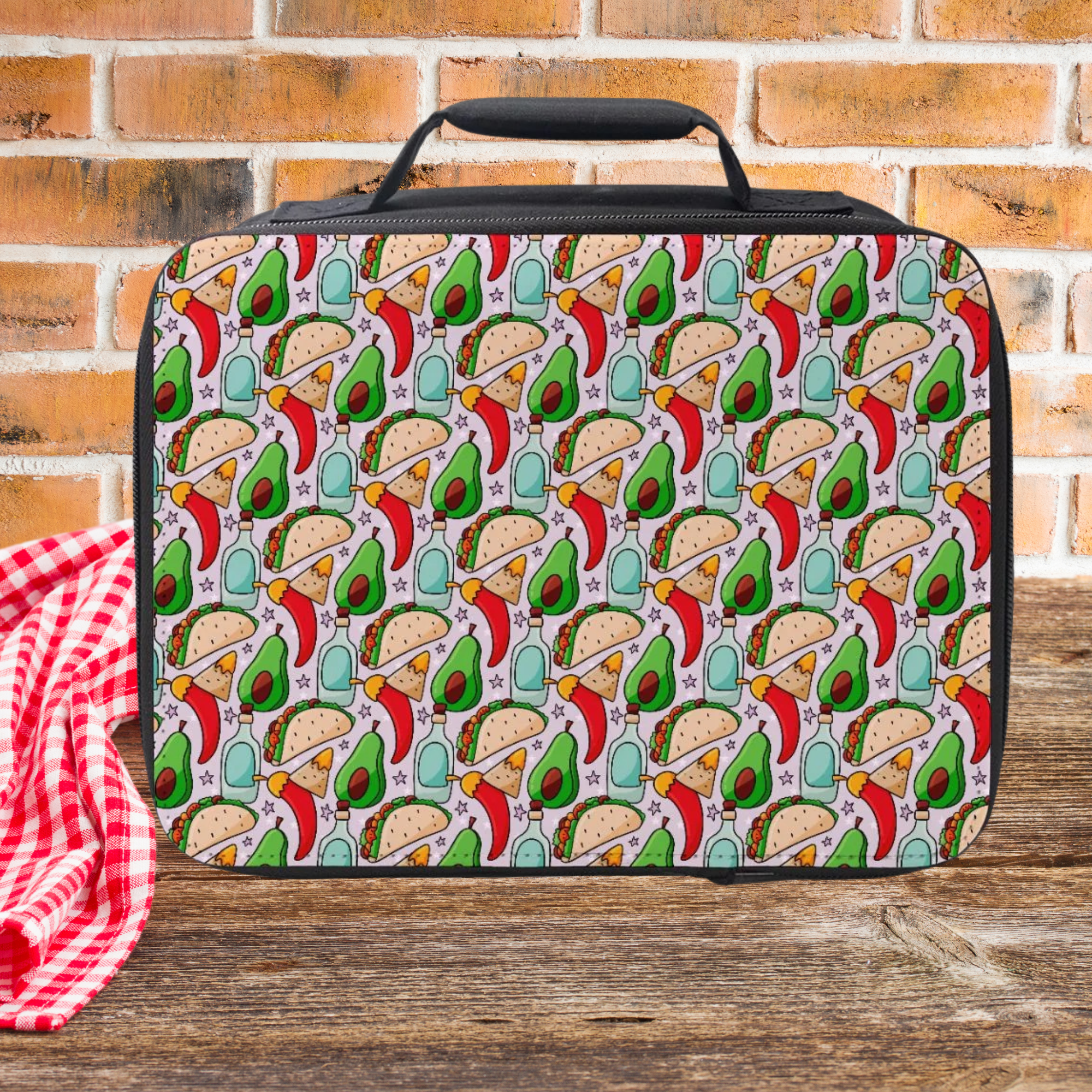 Lunch bag with taco and avocado pattern on a wooden surface with a brick wall background