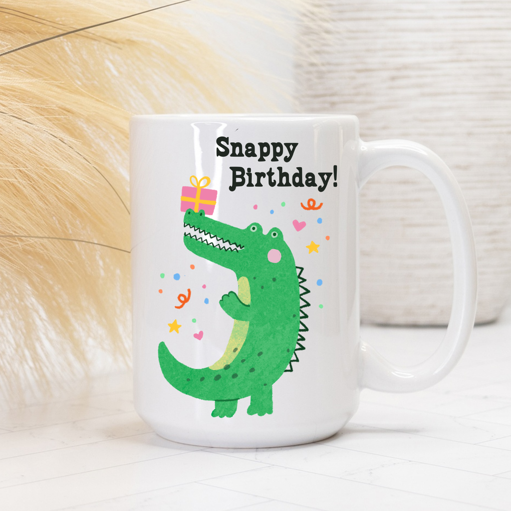 White 15oz. mug with a green alligator design and 'Snappy Birthday!' text on a light background