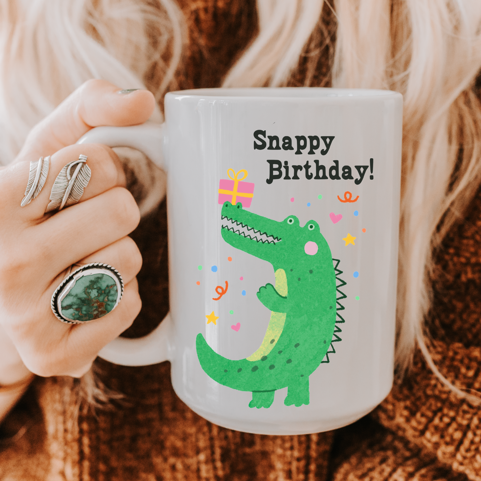 Person holding a 15oz. mug with a green alligator and 'Snappy Birthday!' text.