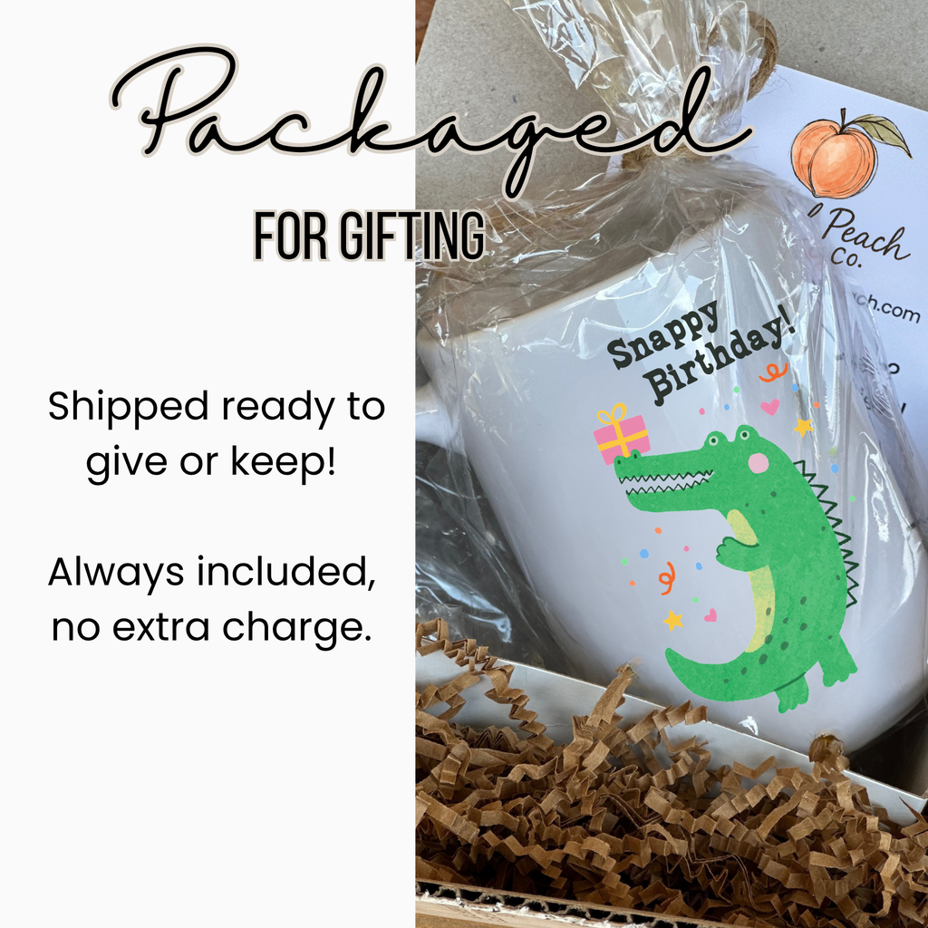 Gift-wrapped 15oz. mug with a crocodile design and 'Happy Birthday!' text, labeled 'Artful Peach Co'.