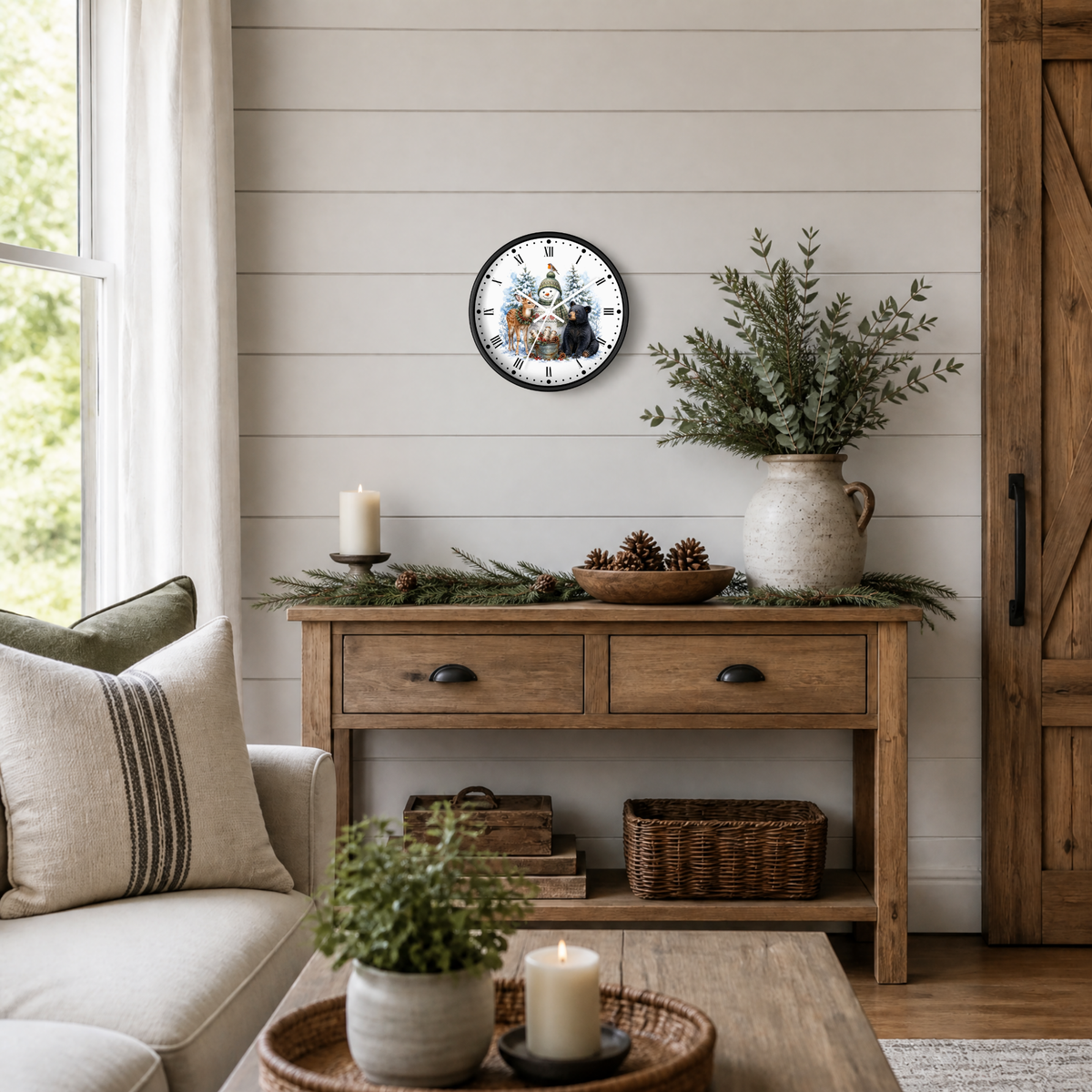 A round wall clock with a rustic holiday illustration of snowman, deer, and black bear, styled on a shiplap wall above a wooden console table in a cozy living room setting.