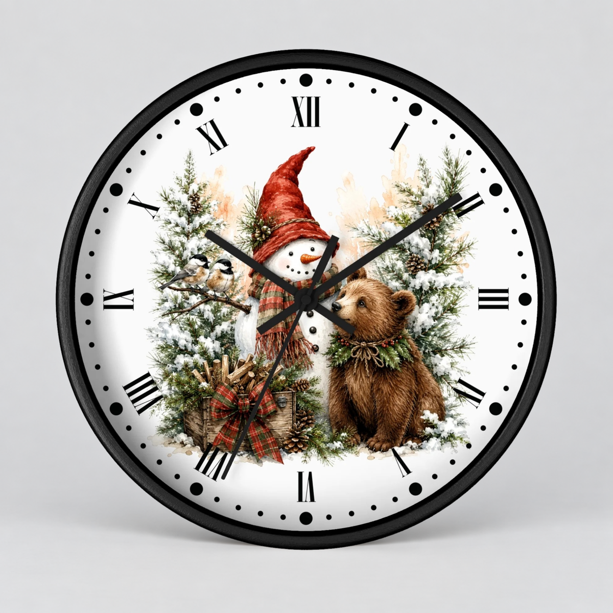 A round wall clock with a black frame and a white face featuring a winter holiday illustration of a snowman in a red hat, a brown bear, pine trees, and a gift box. The clock is shown against a neutral light gray background.