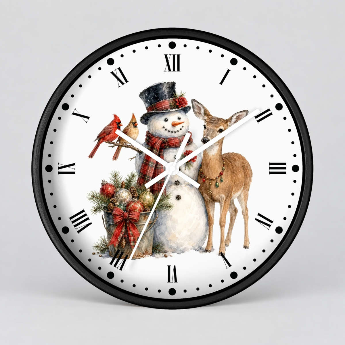A round wall clock with a black frame and white face, featuring a winter holiday illustration of a snowman in a top hat, a deer, two red cardinals, and evergreen branches with ornaments. The clock is shown against a neutral light gray background.