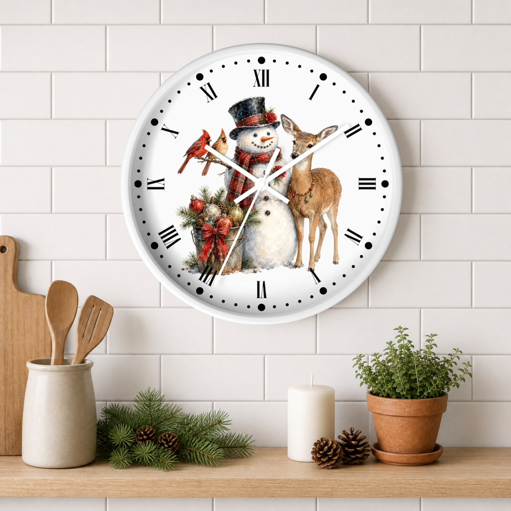 A round white wall clock with a festive winter illustration of a snowman, a deer, a red cardinal birds, and a small tree, mounted on a white subway tile wall above a wooden shelf with kitchen decor.