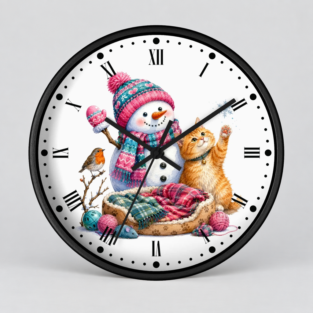 A round wall clock with a black frame and a white face featuring a festive winter illustration. The design shows a snowman in a pink and blue knit hat and scarf, an orange tabby cat, a small bird, and colorful yarn balls, with black Roman numerals around the dial.