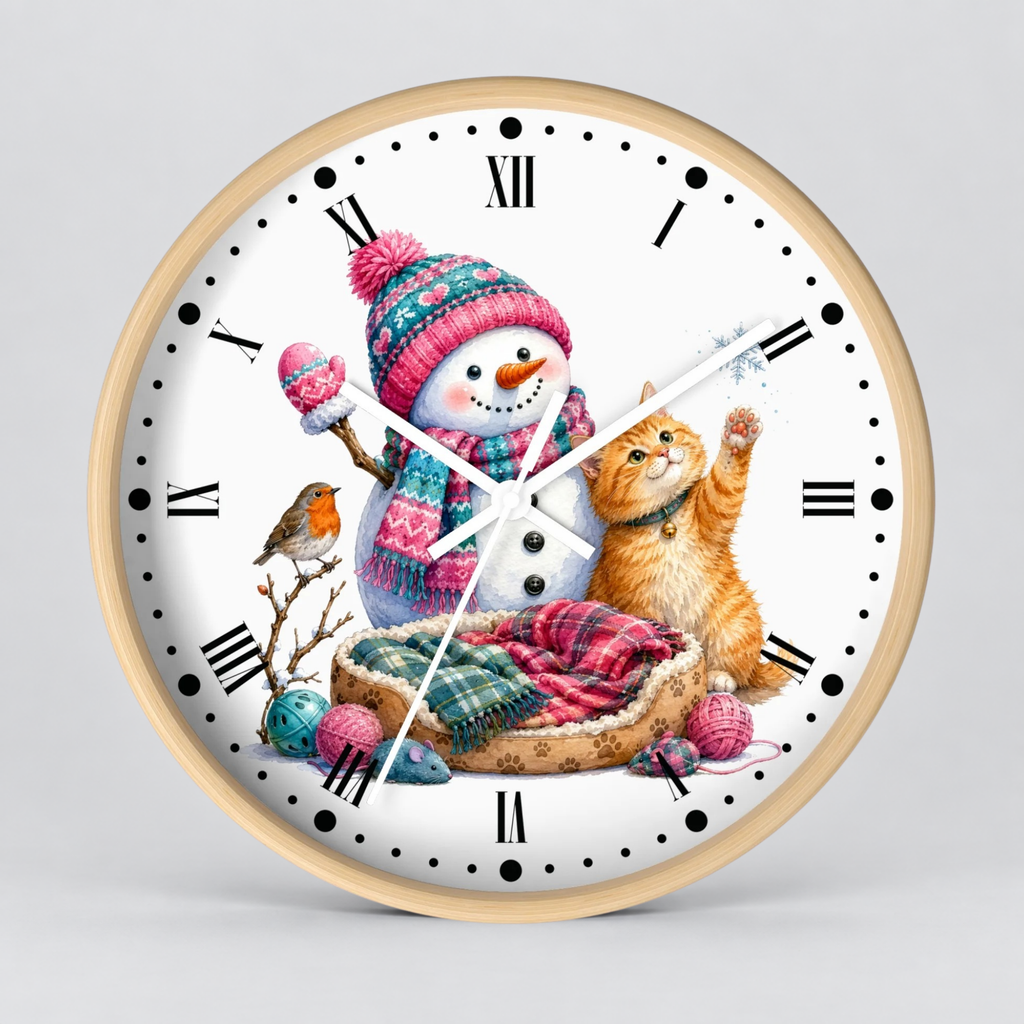 A round wall clock with a light wood frame and a white face, featuring a colorful winter illustration of a snowman in a pink knit hat and scarf, an orange tabby cat, a small bird, and a bed with plaid blankets.