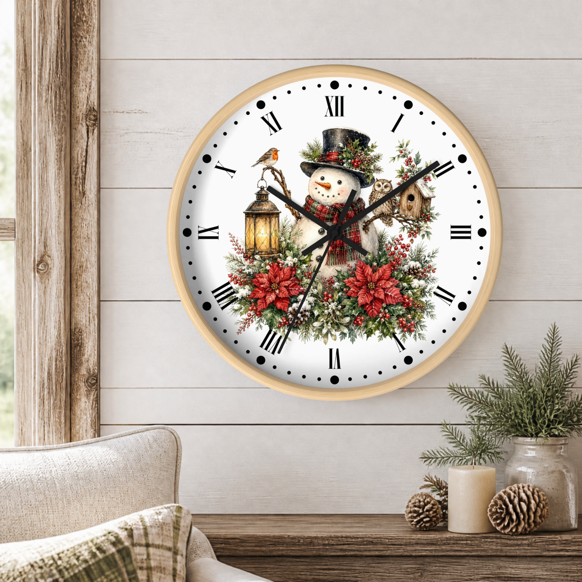 A round wall clock with a light wood frame hangs on a white shiplap wall above a rustic wooden table. The clock face features a festive winter illustration with a snowman wearing a black top hat and red scarf, surrounded by red poinsettias, green holly leaves, a bird perched on a lantern, and a small birdhouse with and owl.