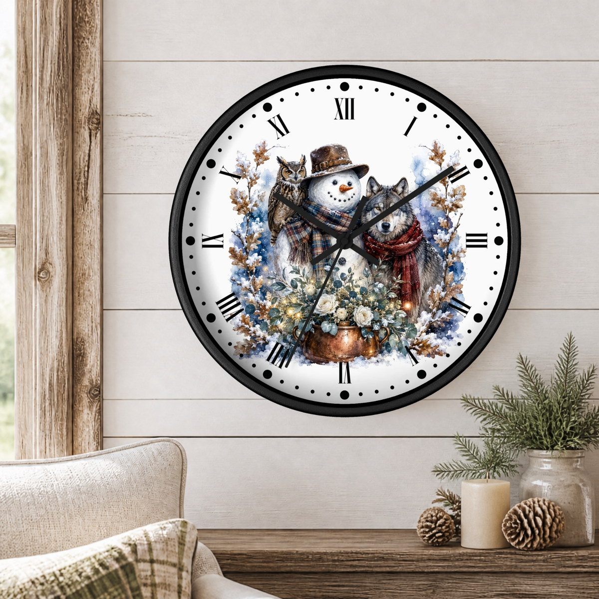 A round wall clock with a black frame and a winter illustration of a snowman, a wolf, and a owl among flowers, mounted on a light wood paneled wall above a table with candles and greenery.