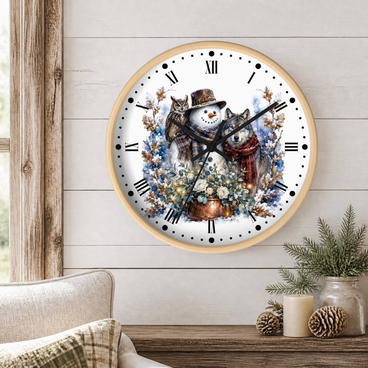 A round wall clock with a light wood frame hangs on a white shiplap wall above a rustic wooden table. The clock face features a detailed illustration of a winter scene with a snowman in a brown hat and red scarf, a gray wolf, blueberries, and a flower pot.