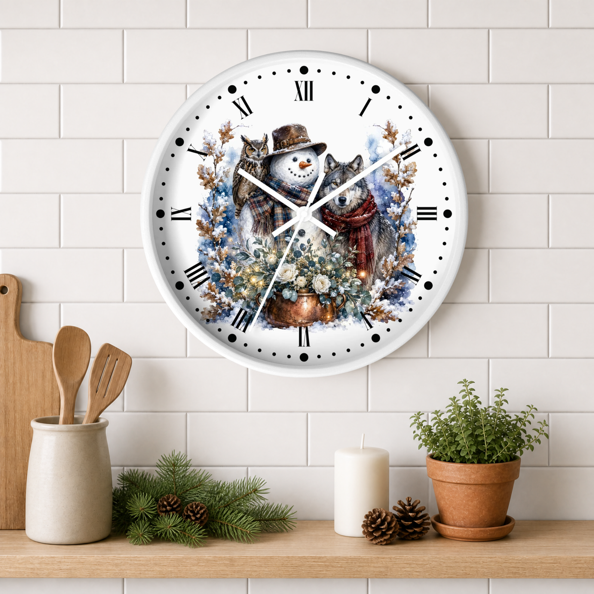 A round white wall clock with a festive winter illustration of a snowman and a wolf, mounted on a white subway tile wall above a wooden shelf with kitchen props and a potted plant.