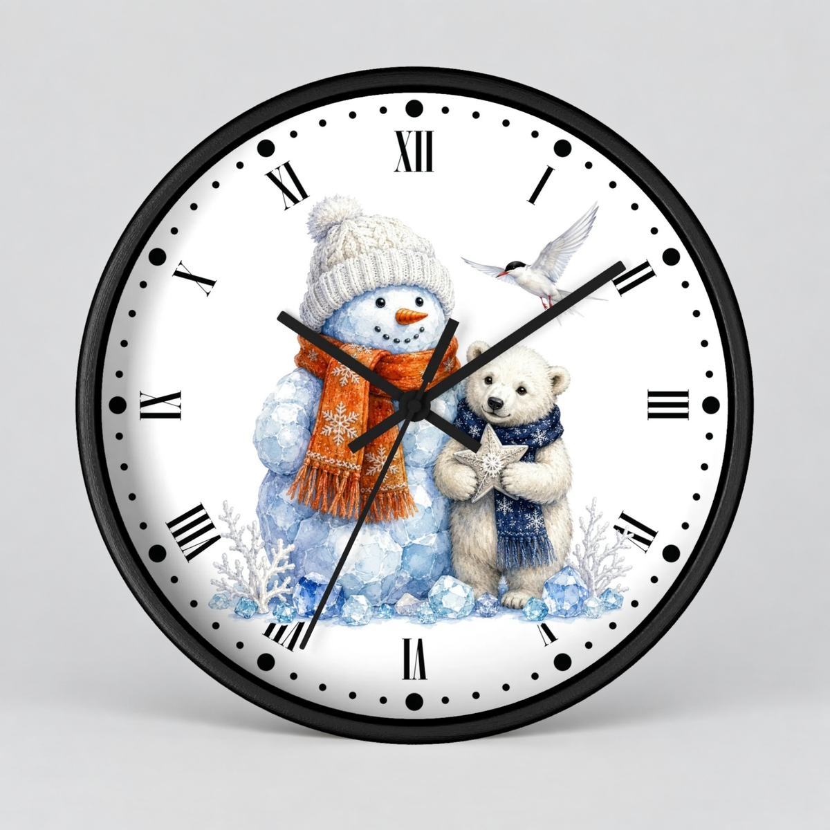 A round wall clock with a black frame and a white face featuring a winter illustration of a snowman in a cream hat and orange scarf, a polar bear in a blue scarf, and a small bird. The clock is shown against a light gray background.