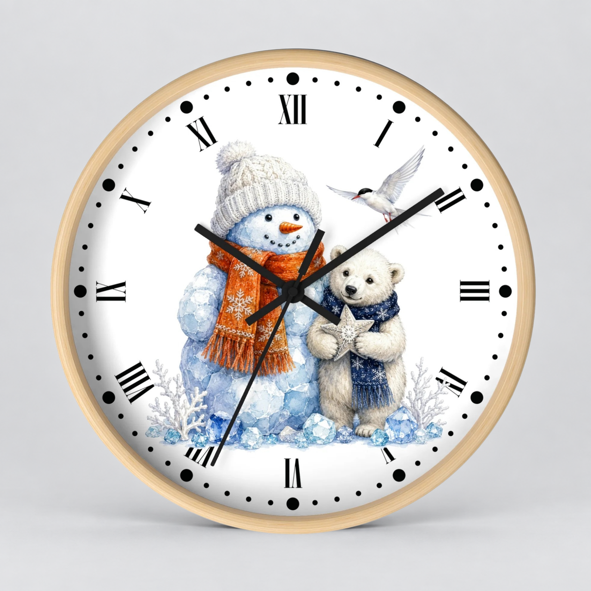 A round wall clock with a light wood frame and a white face featuring a winter illustration of a snowman in a white hat and orange scarf, a polar bear cub in a blue scarf, and a small bird. The clock is shown against a neutral light gray background.