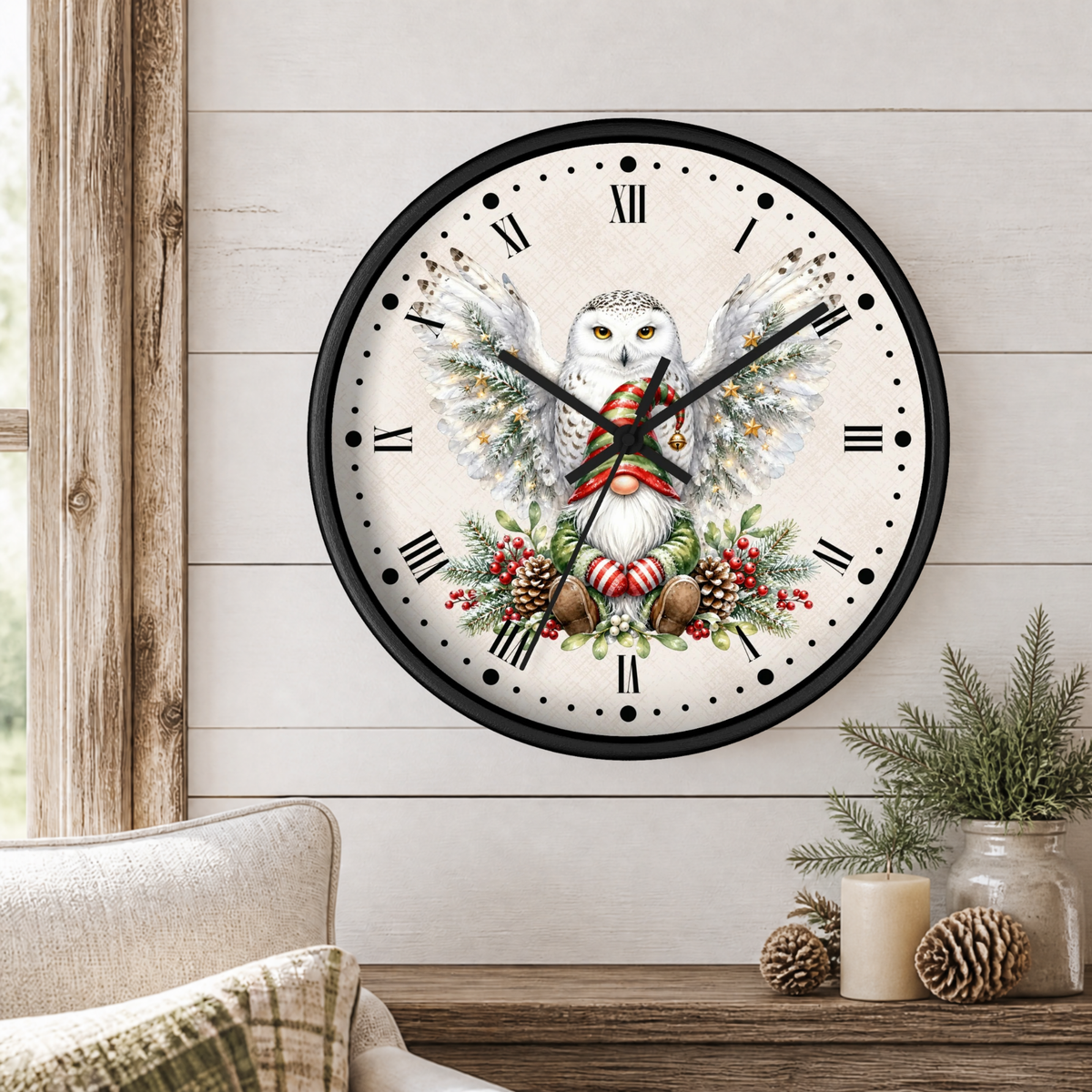A round wall clock with a black frame and a festive owl illustration, displayed on a white shiplap wall above a wooden table with pine branches and candles.