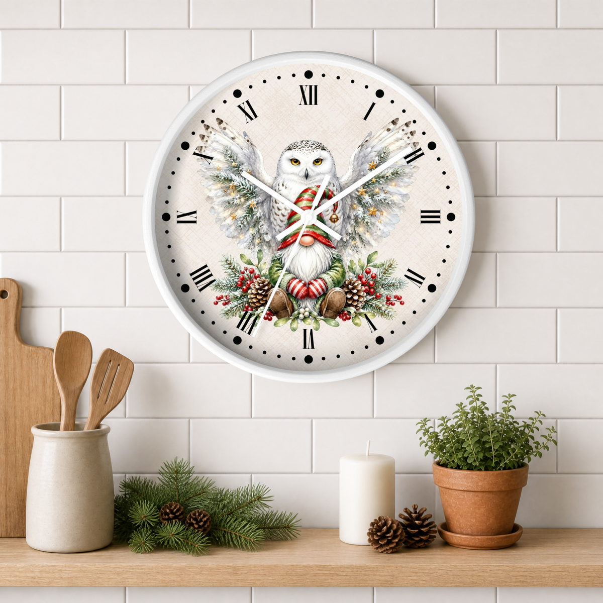 A round wall clock with a white frame and a festive owl illustration on the face, mounted on a white subway tile wall above a wooden shelf with kitchen props including a candle, potted plant, pinecones, and utensils.