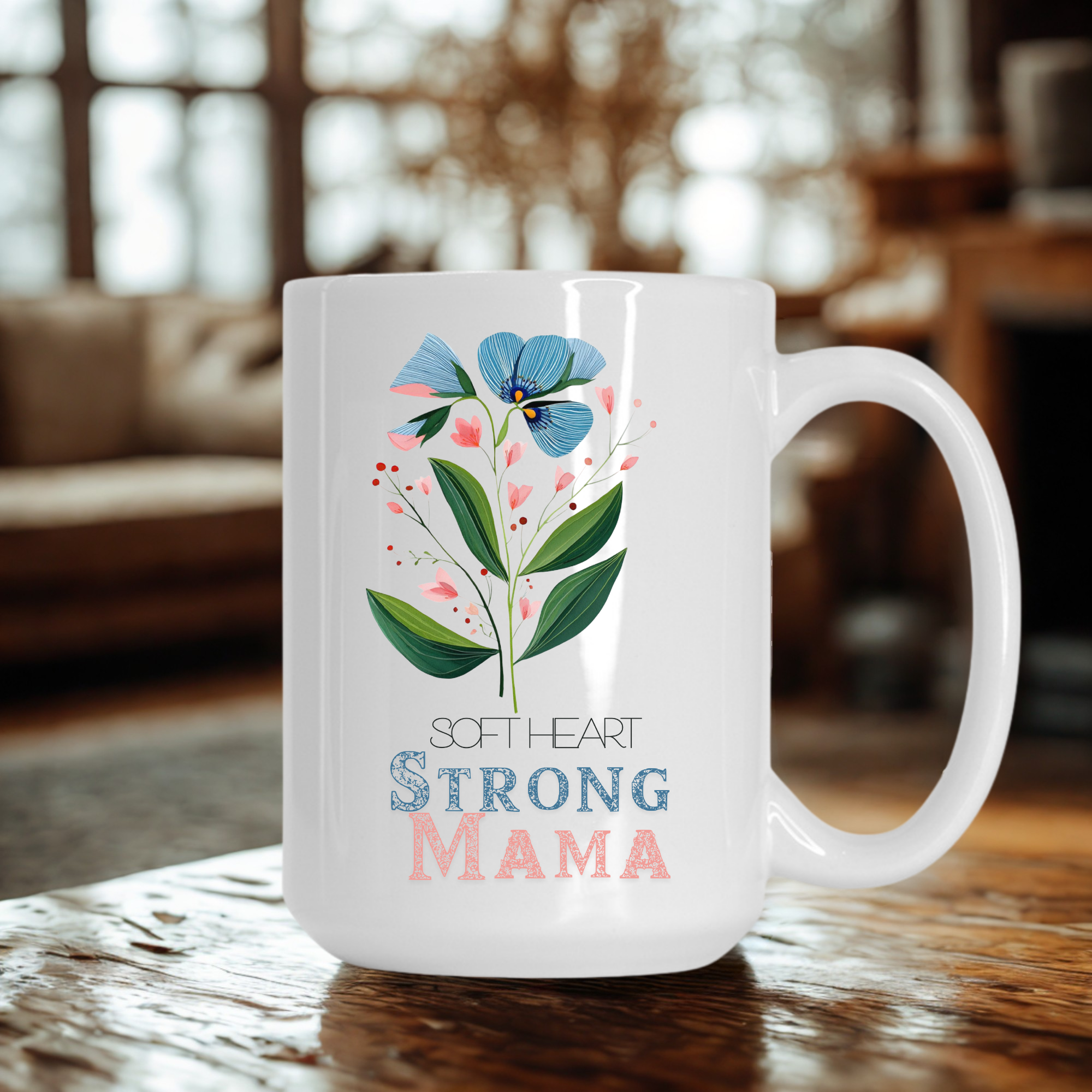 White 15oz ceramic mug with floral design and text 'Soft Heart Strong Mama' on a wooden table.
