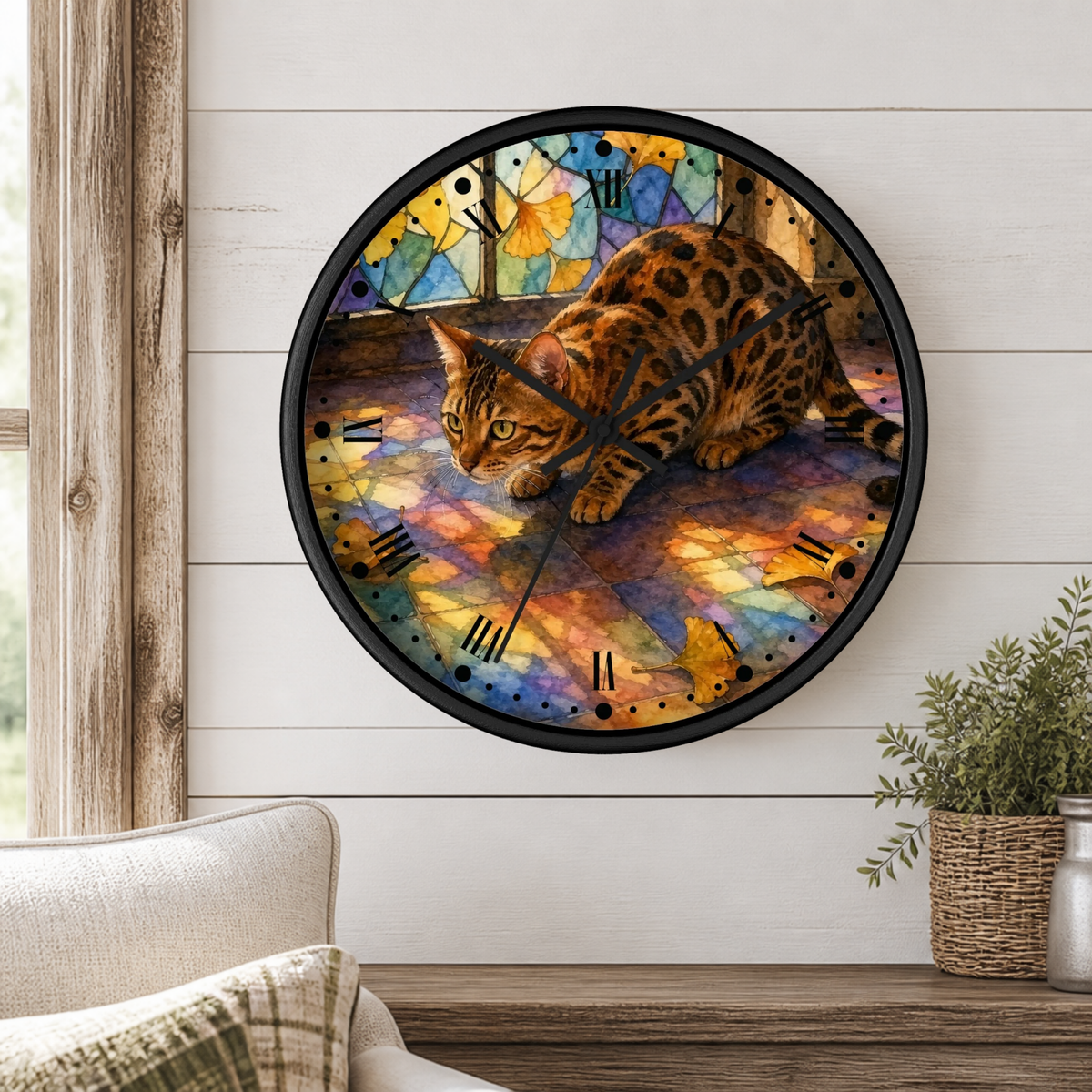 A round wall clock with a black frame and a colorful stained-glass-style design featuring a spotted cat, mounted on a white shiplap wall above a wooden mantel with a plant.
