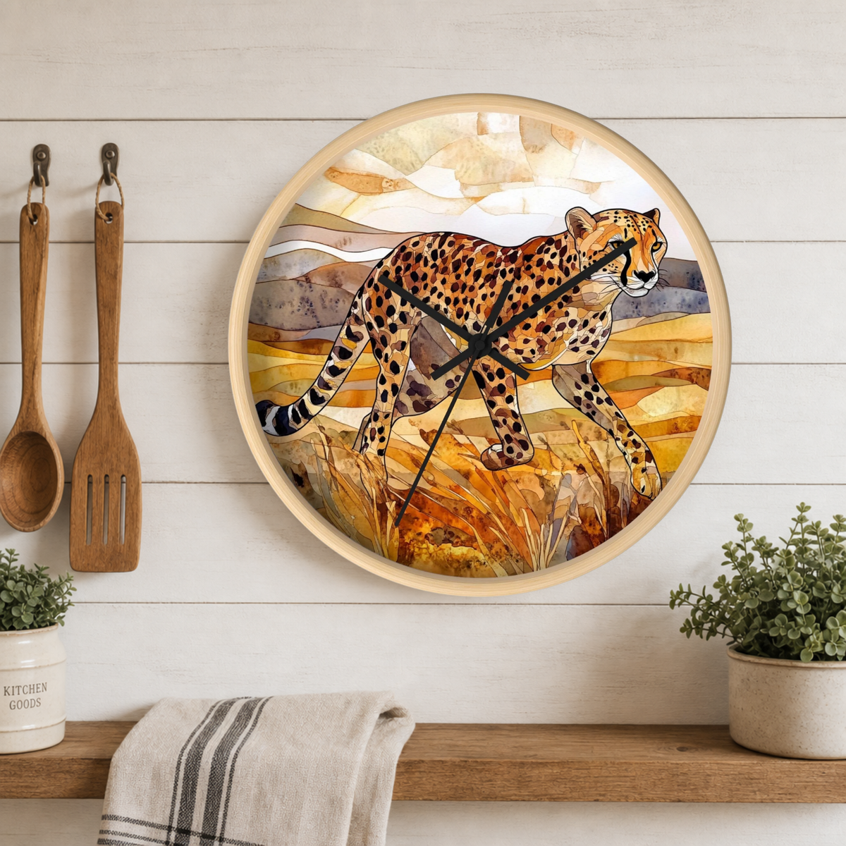 Round wall clock with a cheetah illustration on the face, mounted on a white wood plank wall above a wooden shelf with plants and kitchen utensils.