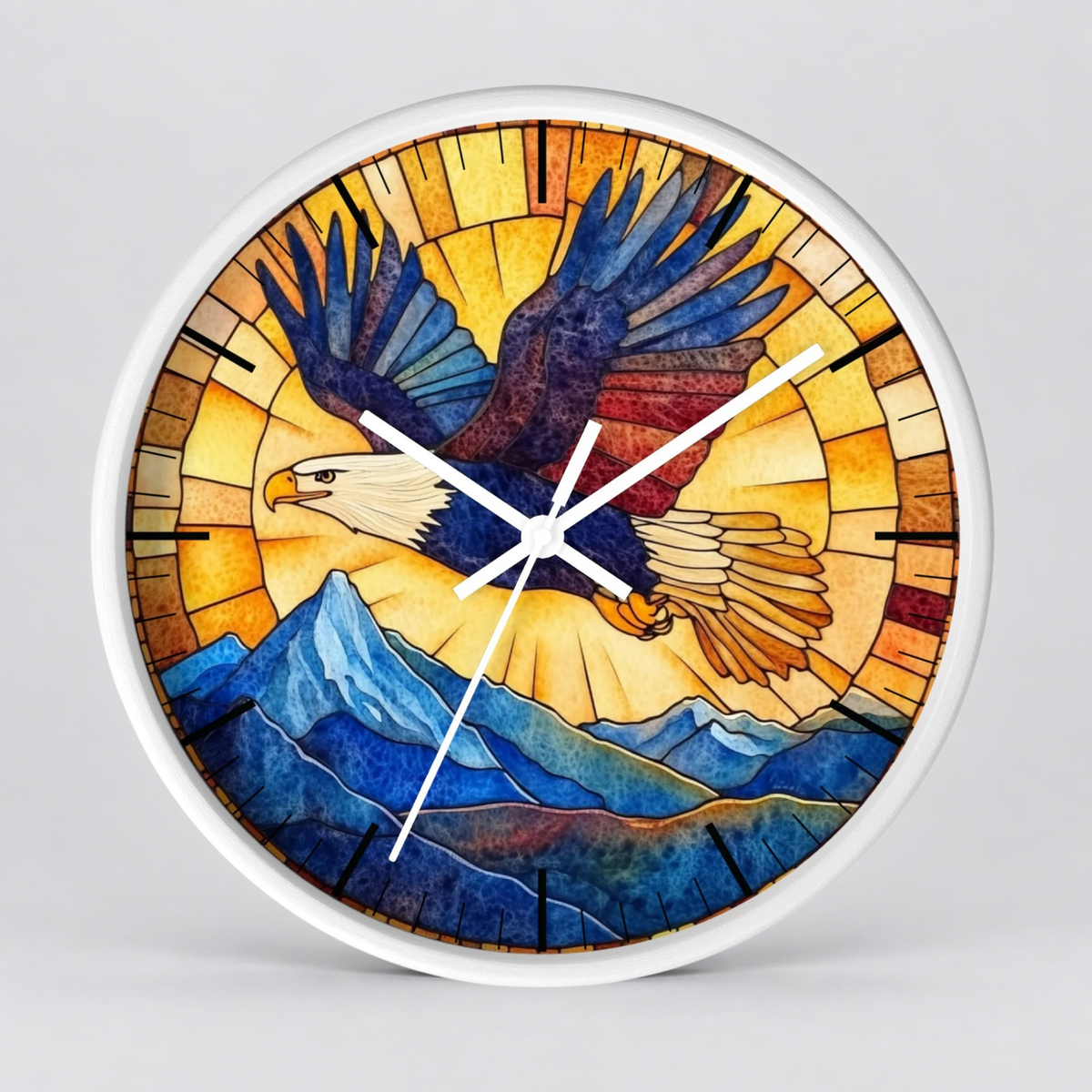 Round wall clock with a white frame and a stained-glass-style design featuring a bald eagle flying over blue mountains, shown on a light gray background.