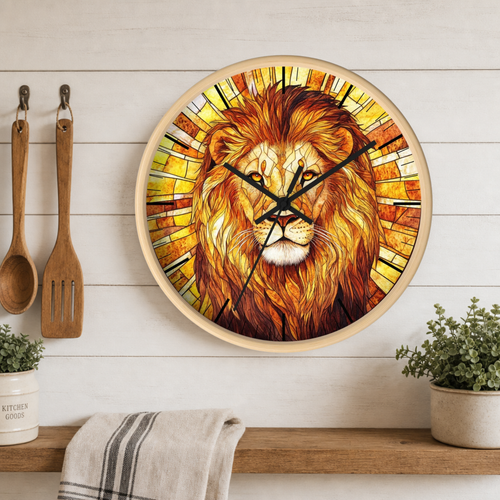 Round wall clock featuring a stained-glass-style lion portrait in warm yellow, orange, and brown tones, mounted on a white wood plank wall above a shelf with kitchen utensils and small plants.