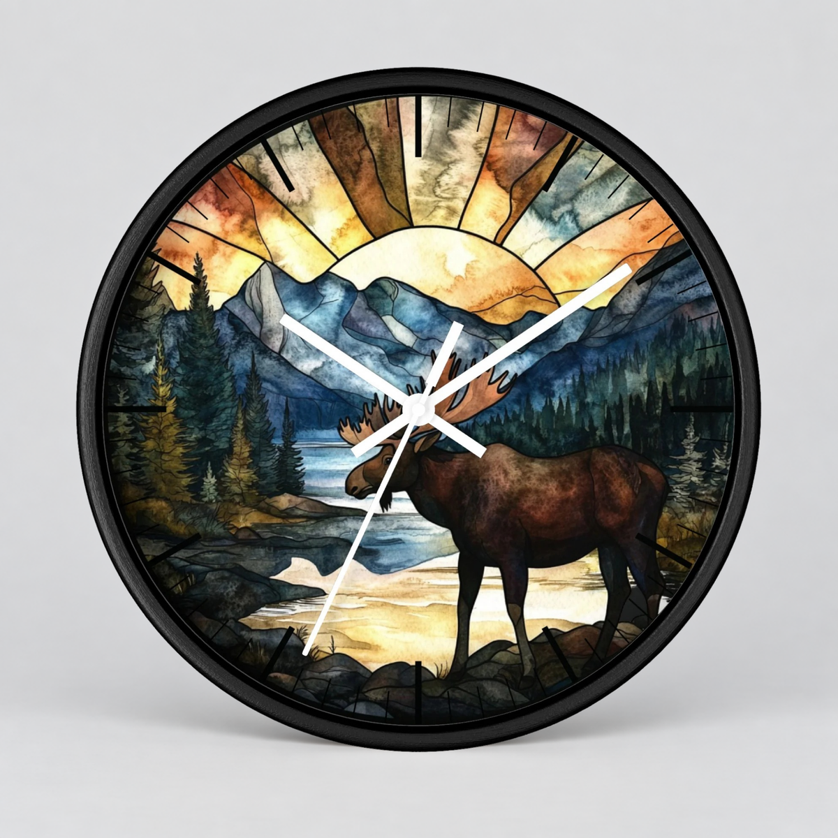 A round wall clock with a black frame and white hands, featuring a stained-glass-style scenic print of a moose in a forest by a river with mountains and a glowing sun.