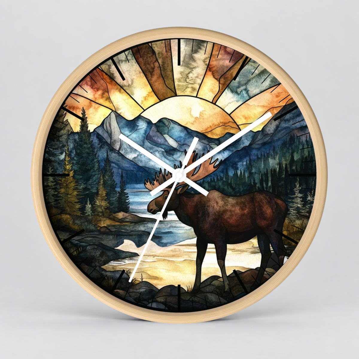 Round wall clock with a light wood frame and a stained-glass-style illustration of a moose in a mountain landscape at sunset, shown on a light gray background.