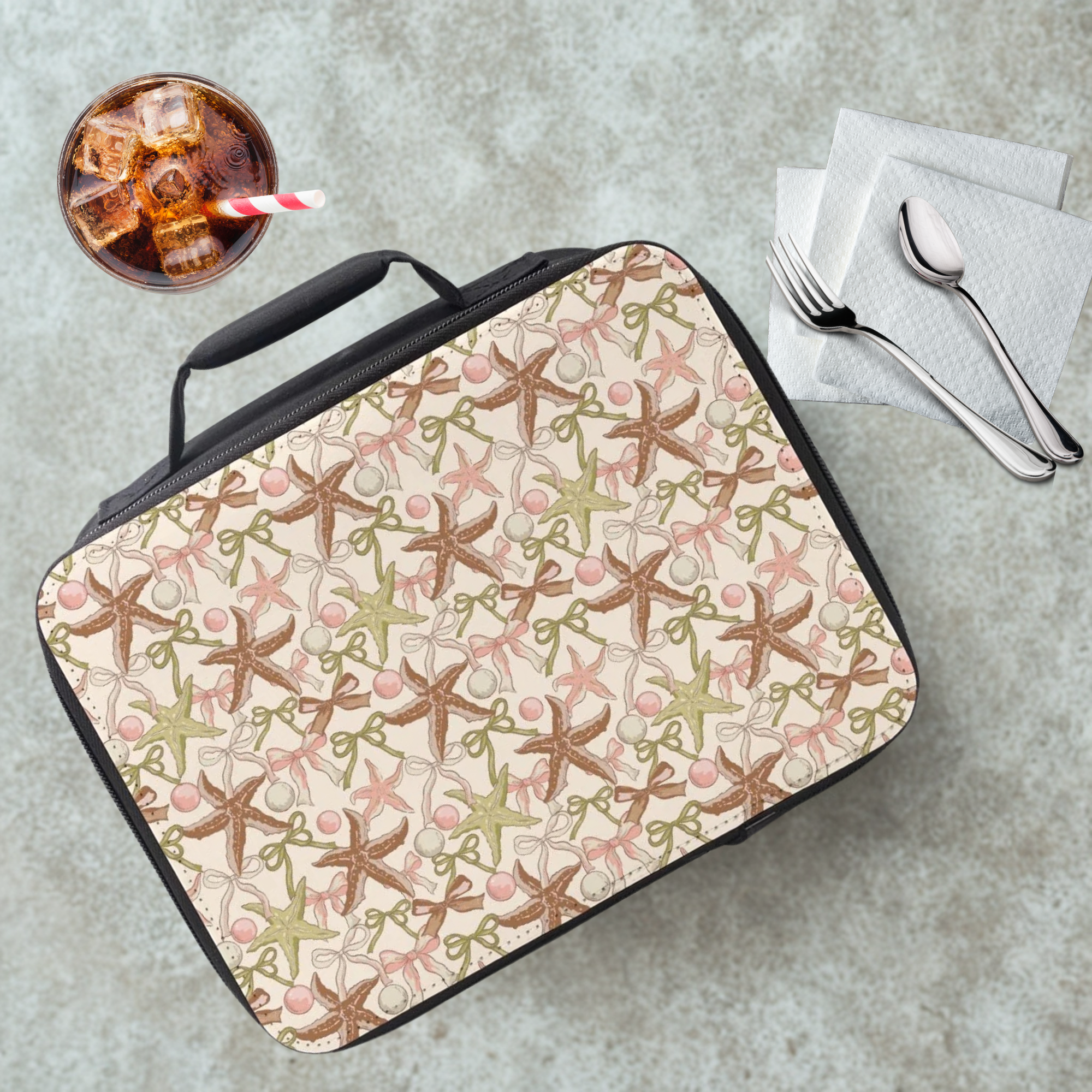 Lunch bag with starfish pattern on a cafeteria table with a drink and utensils.