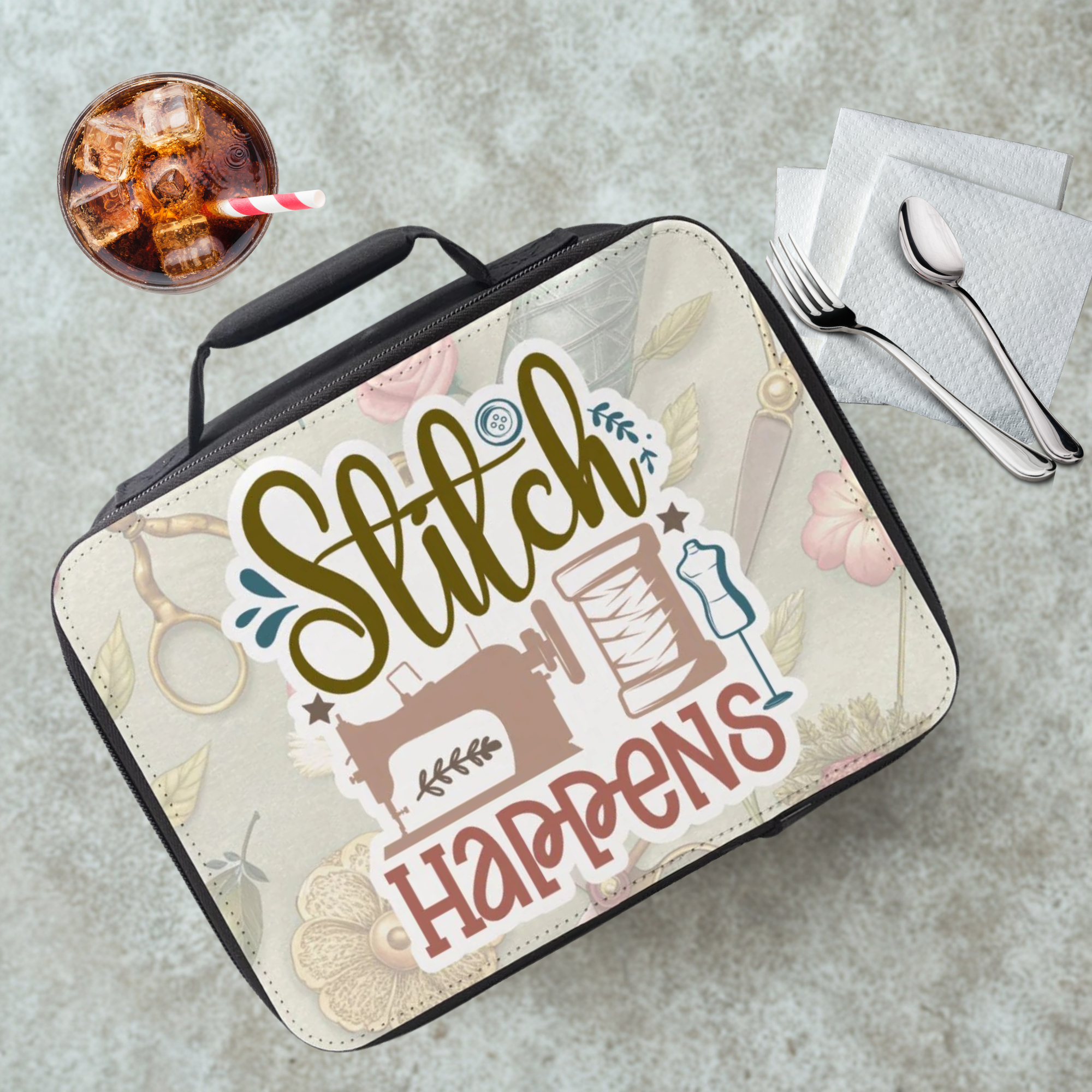 Lunch bag with 'Stitch Happens' design on a table with a drink and utensils.
