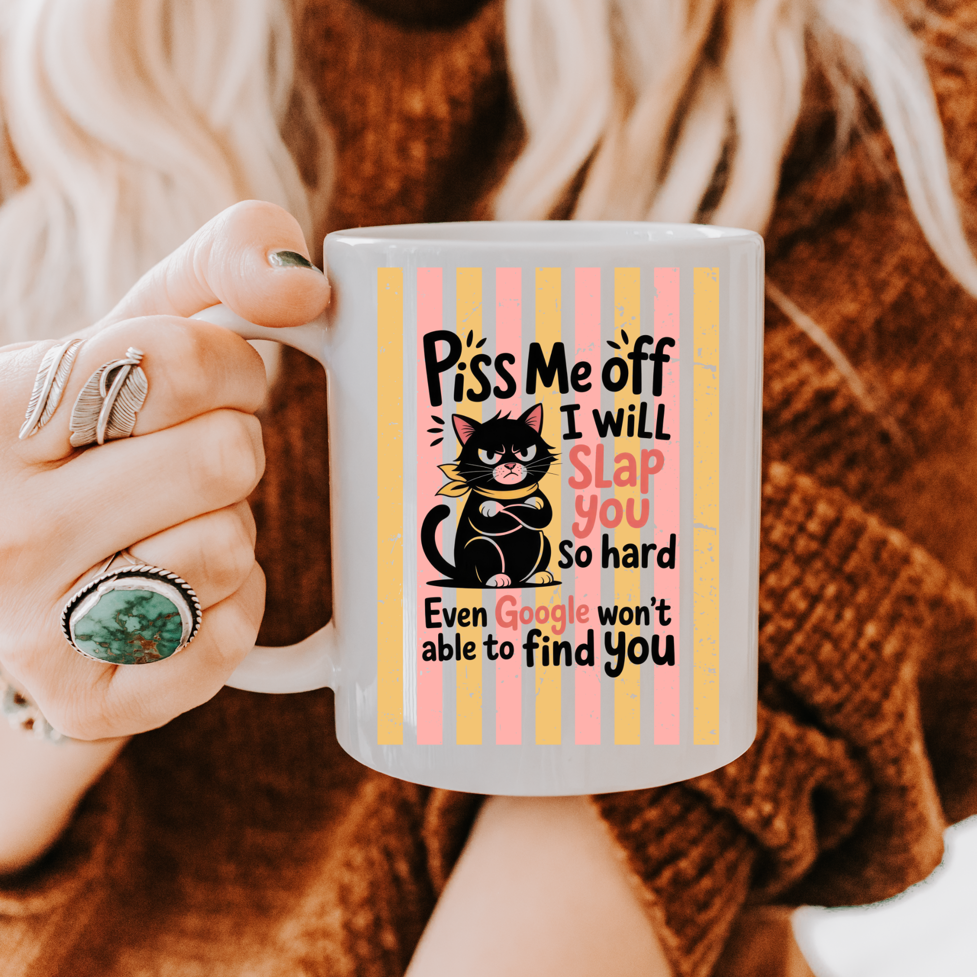 Person holding a mug with a humorous cat design and text.