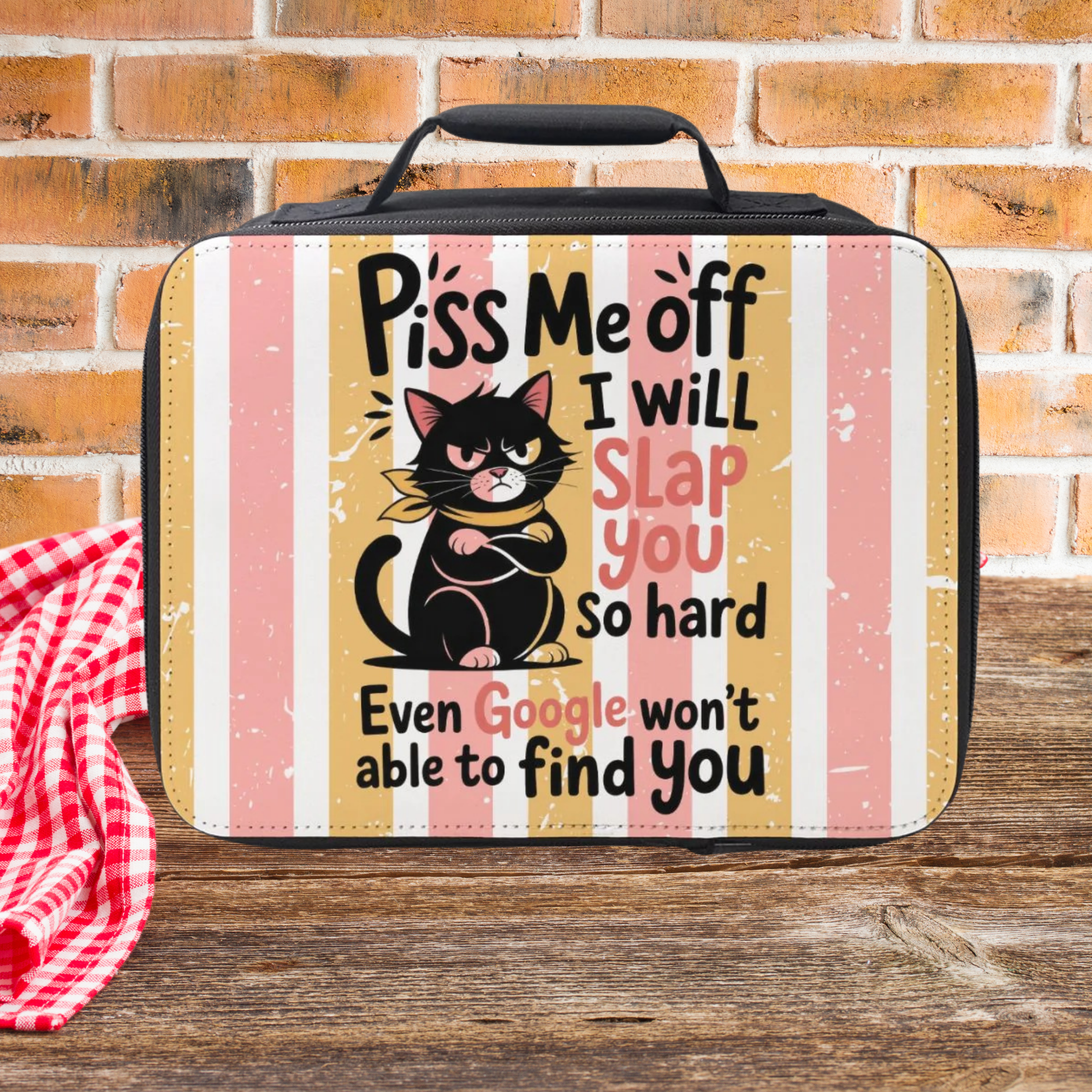 Lunch bag with a black cat graphic and humorous on a striped background with  text on a wooden picnic table against a brick wall background