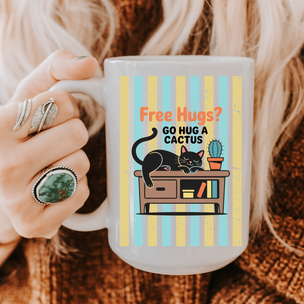 Person holding a 15oz mug with a cat and cactus design and text 'Free Hugs? Go hug a cactus'.