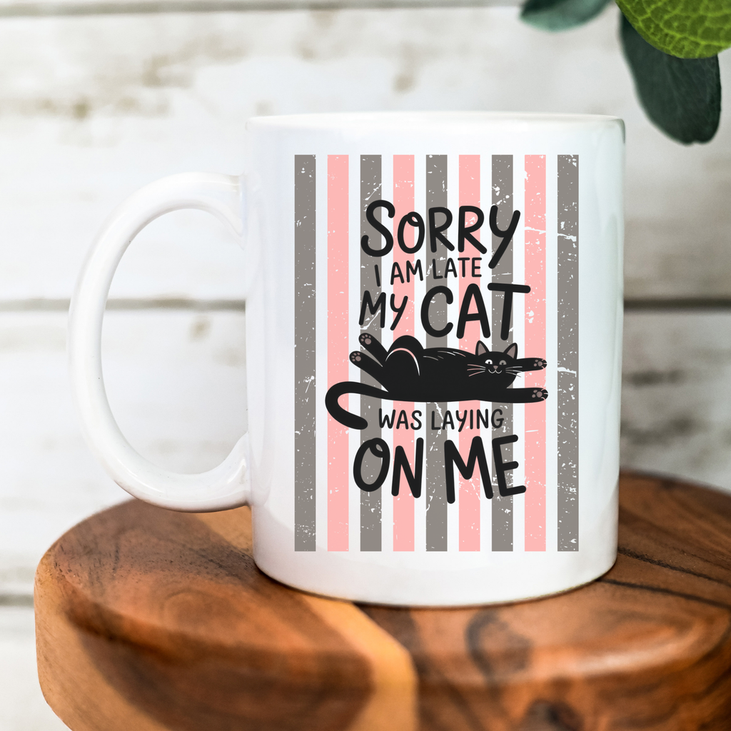 White 11oz mug with a humorous design of a cat and text on a striped background, placed on a wooden surface.
