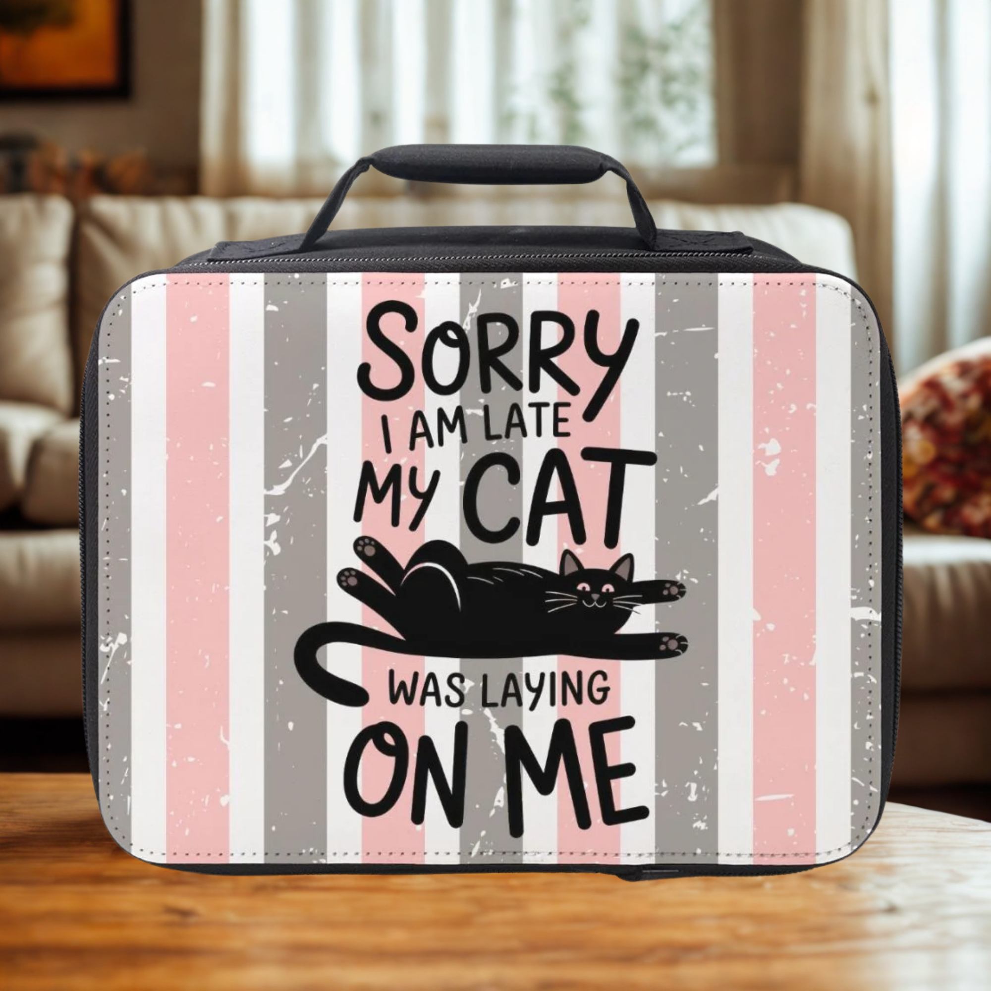 Black lunch box with striped design and text about a cat on a wooden living room table.