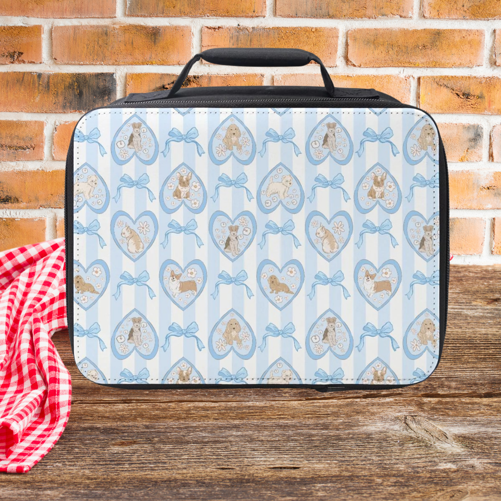 Lunch bag with hearts, dogs, and bows pattern on a wooden picnic table with a brick wall background